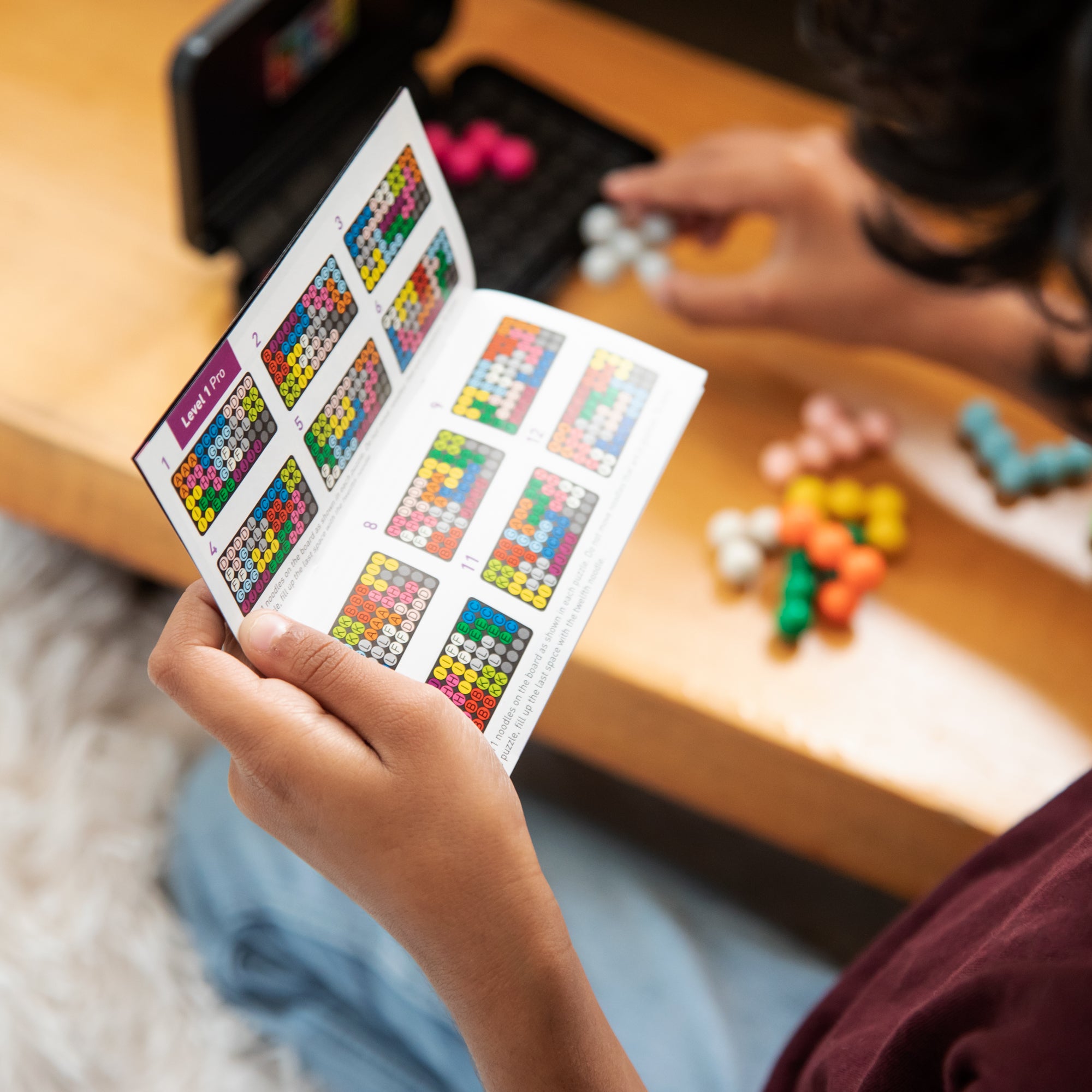 A child reading a Kanoodle Game booklet