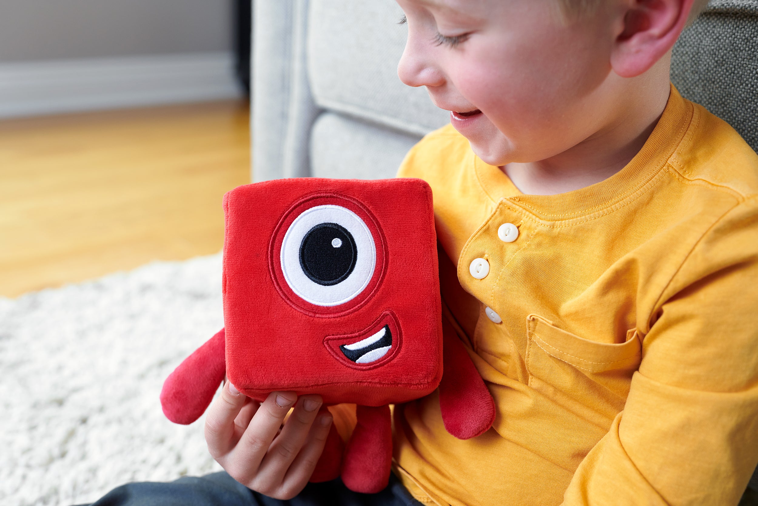 A child caressing the Numberblocks Number One Plush Toy