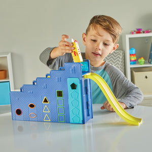 A young child preparing to slide the Numberblock 3 figure down the Numberblocks Step Squad Mission Headquarters slide attachment